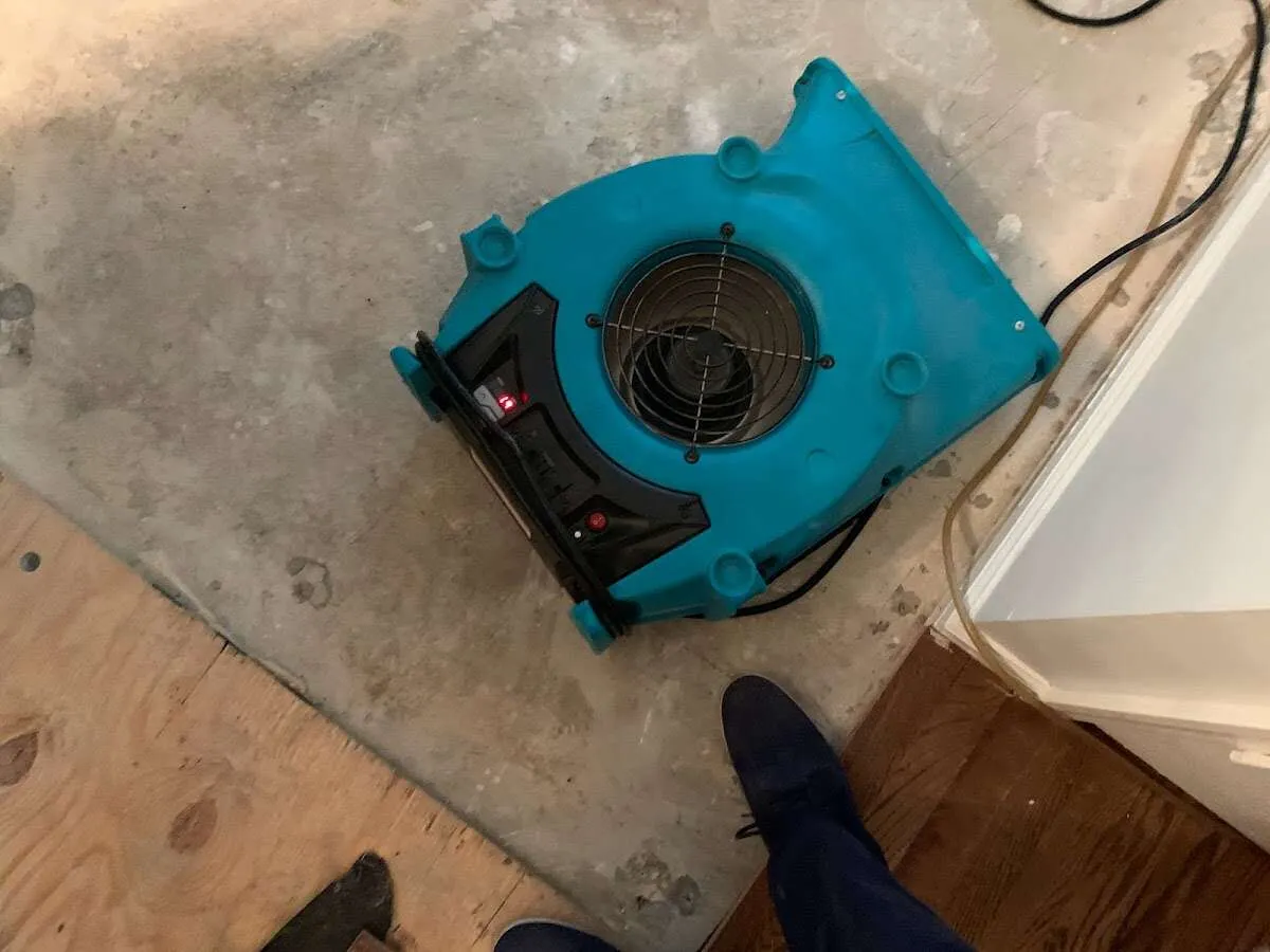 Air mover drying subfloor during Commercial Water Damage Restoration in Center Point